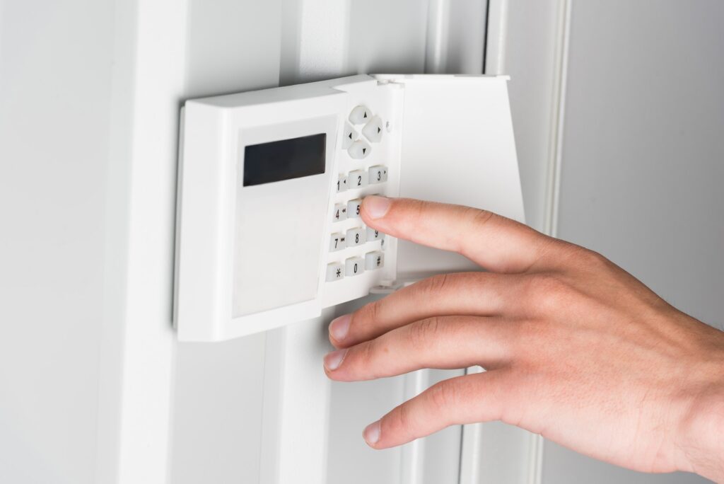 cropped view of person typing password on home security alarm, security system concept